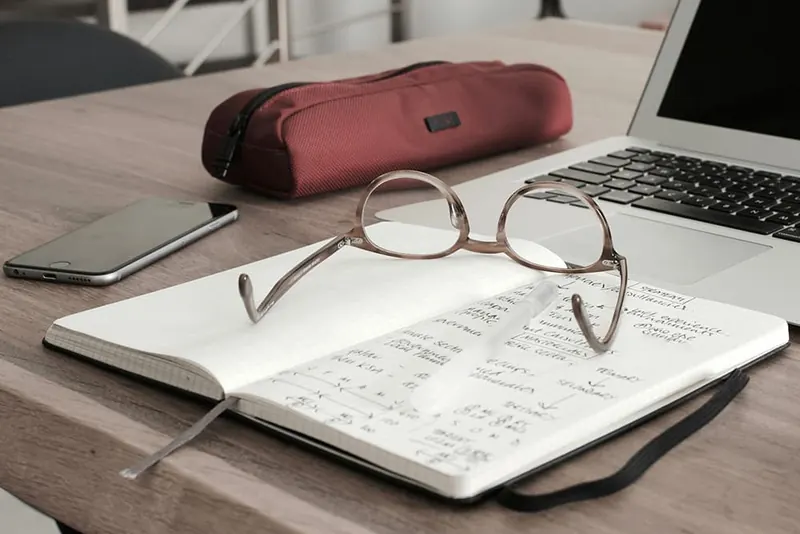 Exact Online als boekhoudprogramma Opengeslagen notitieboek met bril naast een laptop op een houten bureau